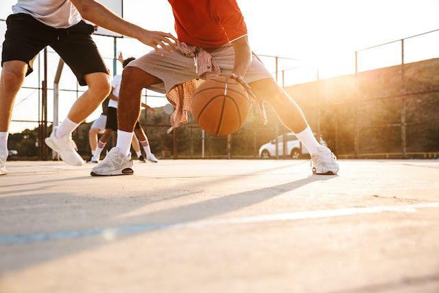 Un uomo in pantaloncini grigi e una maglietta rossa dribbla una palla da basket.